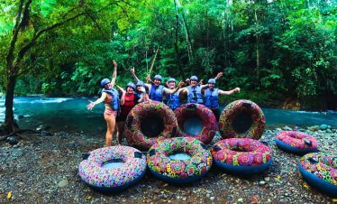 a group of people standing next to a group of rubber tubes