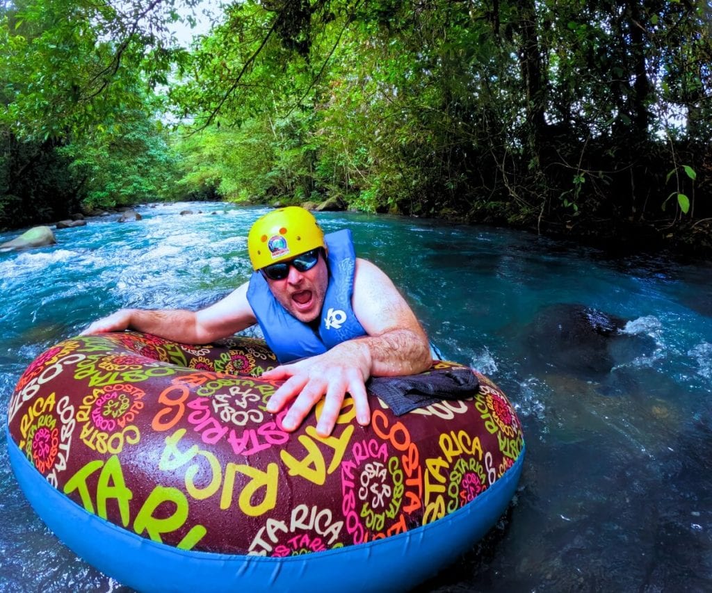 a man in a life jacket on a tube in a river