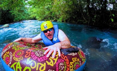 a man in a life jacket on a tube in a river